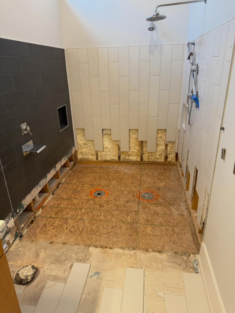 A bathroom shower area undergoing renovation with new tiling and exposed subfloor by Rice Building Company in Rocky Mount, NC.