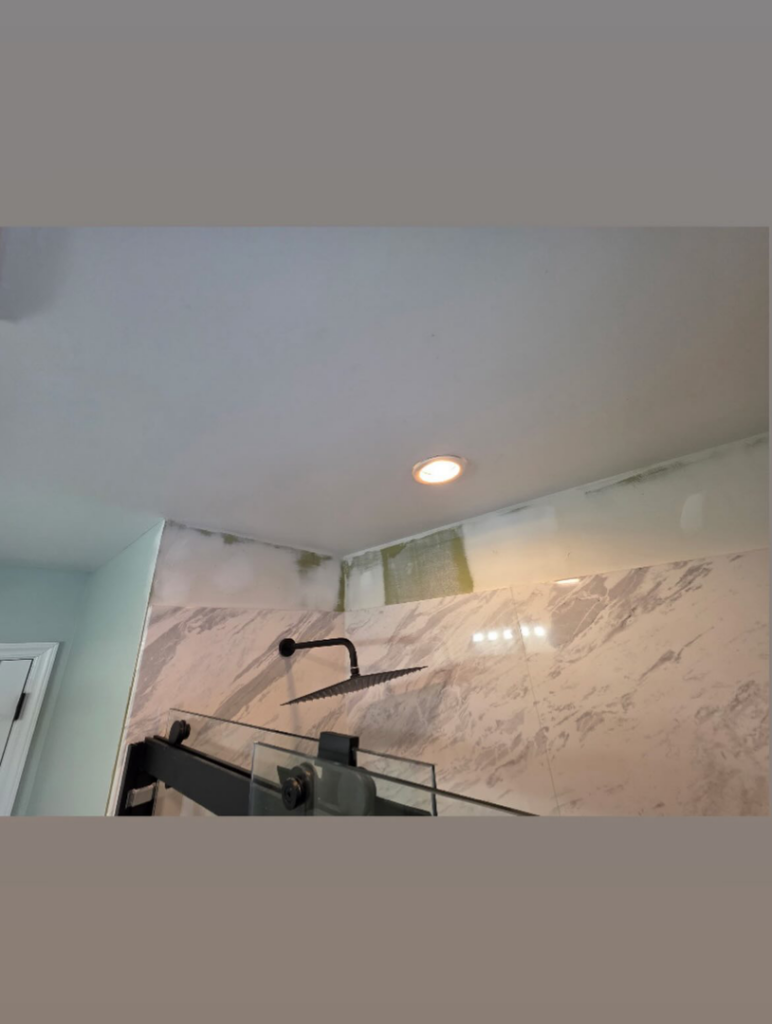 A bathroom shower renovation in progress, showing exposed drywall above new tiles by Precision Property Services LLC in South Windsor, CT.