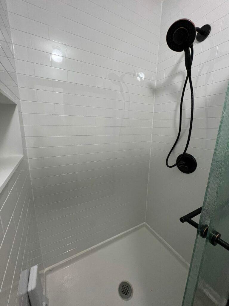 A newly renovated walk-in shower with white subway tiles by Thrive Homes, LLC in Olathe, KS.