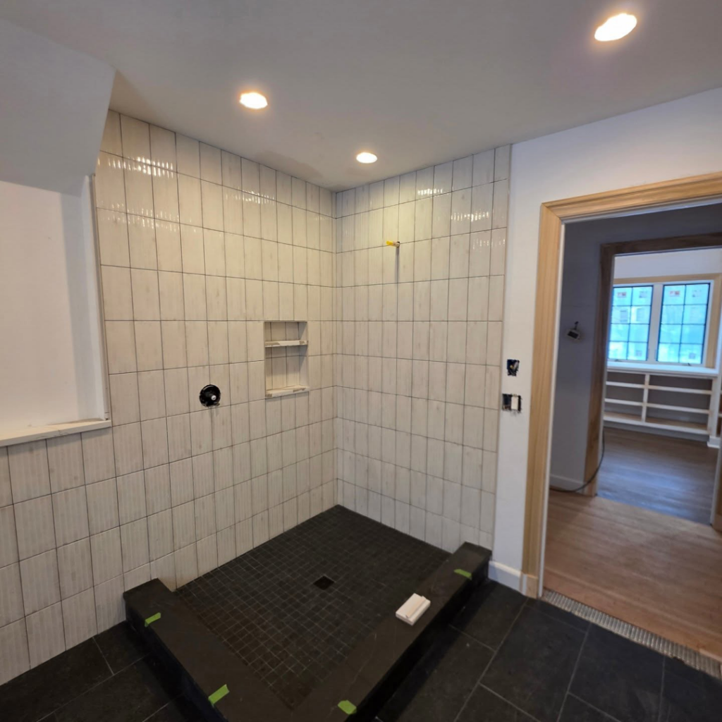 A bathroom shower area under renovation with new tiling and shower pan, completed by Ember Works in Rochester, NY.