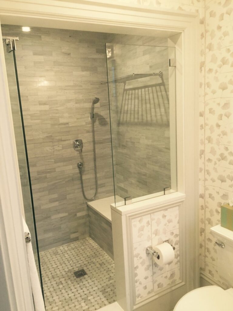 A newly installed bathroom shower with modern tile and glass enclosure by Connaughton Construction in Waltham, MA