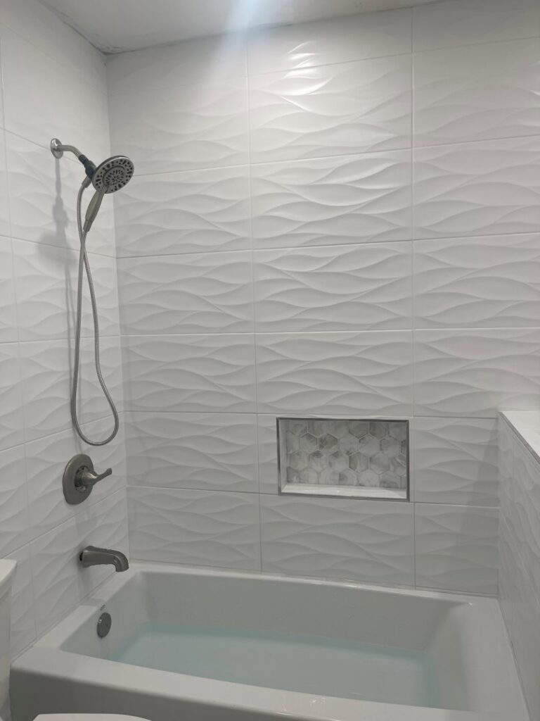 A modern bathroom featuring new white wavy tile in the shower and bathtub area, a renovation by M7 Remodel & Restoration Inc. in Houston, TX