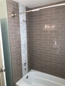 Bathroom shower with grey subway tiles and a mosaic accent strip, expertly installed by The Huckleberry Handyman in Meridian, ID.