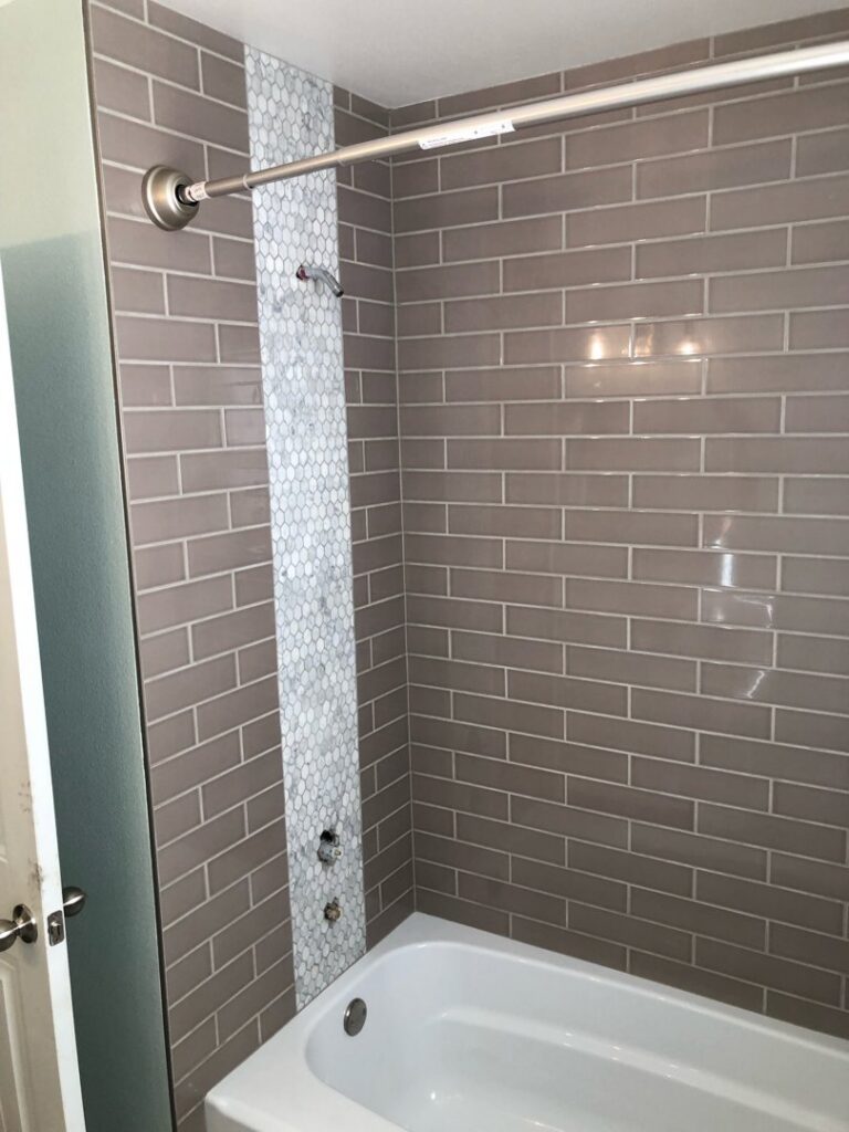 Bathroom shower with grey subway tiles and a mosaic accent strip, expertly installed by The Huckleberry Handyman in Meridian, ID.