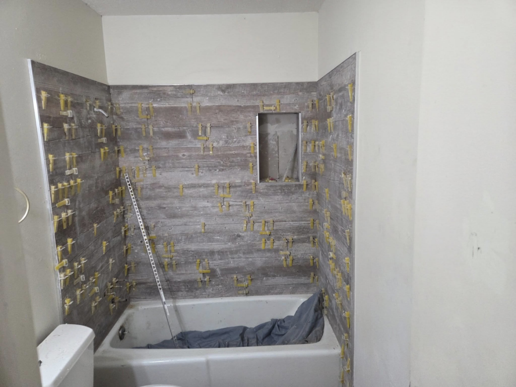 Bathroom shower wall tiling in progress with spacers, demonstrating work by Joel's flooring & Handyman services in Roy, UT.