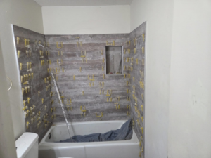 Bathroom shower wall tiling in progress with spacers, demonstrating work by Joel's flooring & Handyman services in Roy, UT.