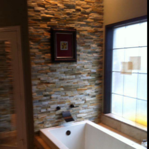 A bathroom featuring a stacked stone accent wall and a modern bathtub by Mason Contracting in Levittown, PA.