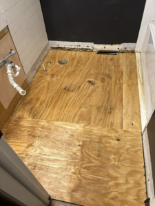 A bathroom subfloor with exposed plumbing pipes, ready for new flooring installation by CJ Flooring LLC in Flat Rock, MI.