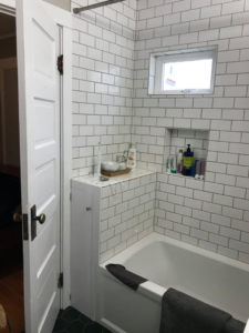 A newly tiled bathroom with a bathtub and built-in niche installed by Kaya Construction in Portland, OR.