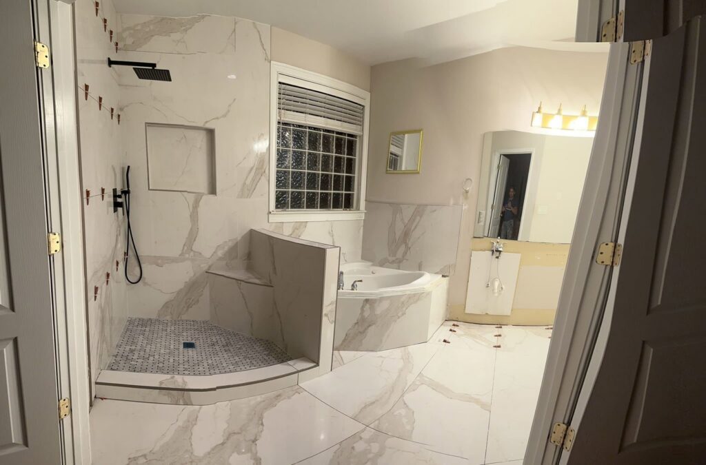 A bathroom undergoing renovation with new white marble-look tile installation by Glenni Floors LLC in Roswell, GA.