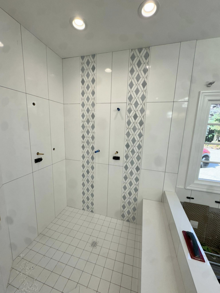 Bathroom tile installation in progress with white and patterned grey tiles by Bohannon Custom Tile and Renovation in Virginia Beach, VA.