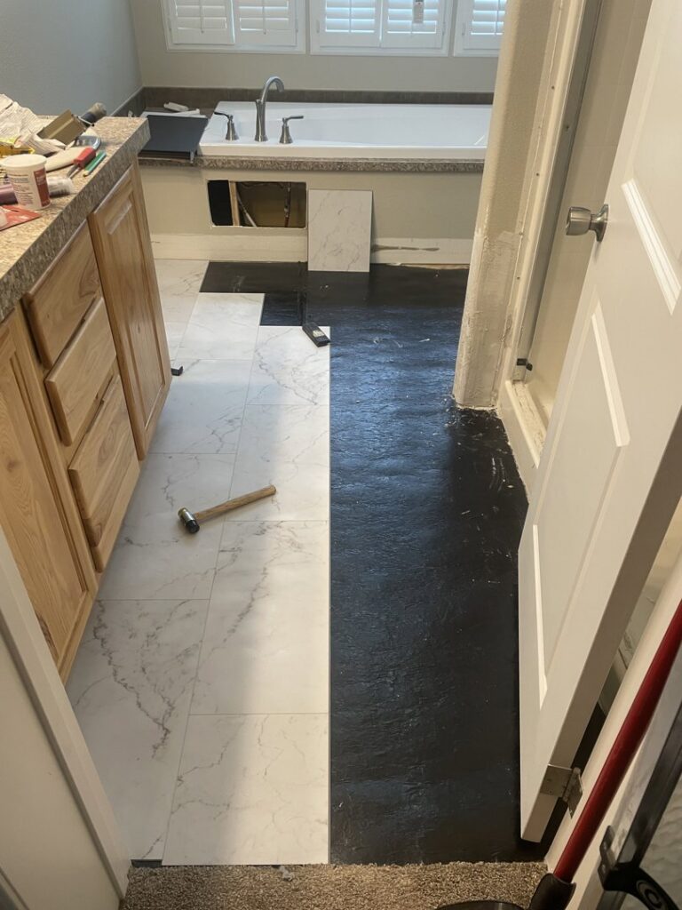 New white marble-look tiles being installed on a bathroom floor, showing work in progress by Knutson's Property Maintenance Llc in Williston, ND.