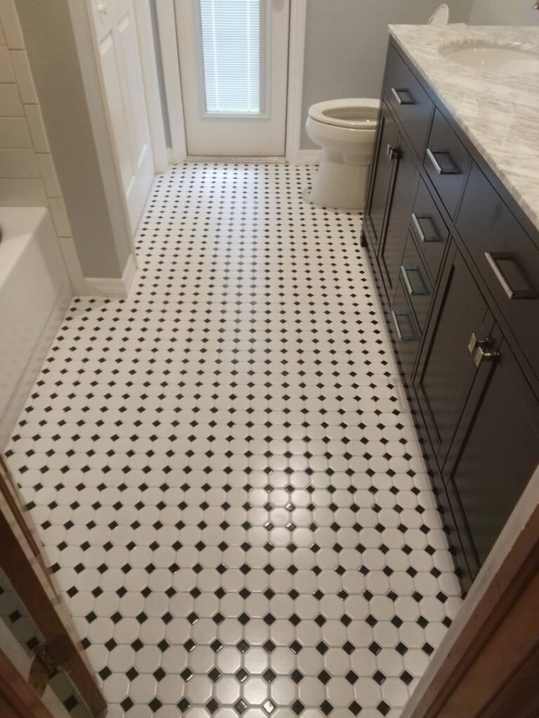 A newly tiled bathroom floor with black and white hexagonal tiles, installed by Serene Construction, LLC in Richmond, VA.