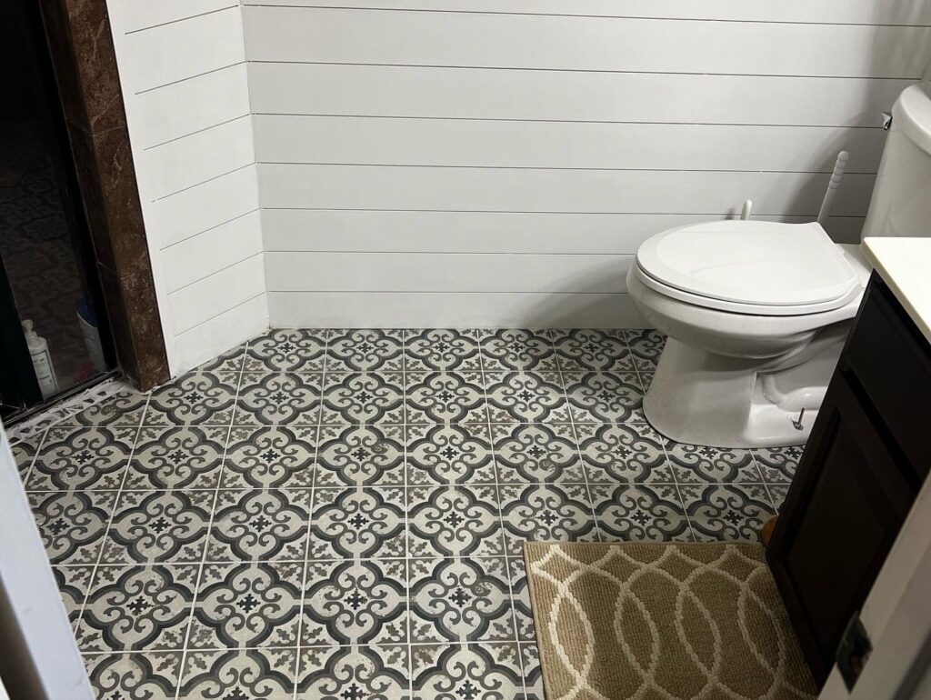 A renovated bathroom showcasing new patterned floor tiles and modern shiplap walls by Lay's Remodeling LLC in El Paso, TX