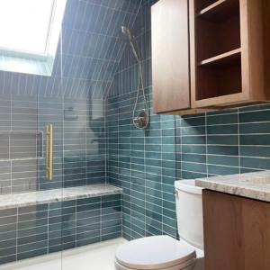 A bathroom featuring blue tiled walls, a shower with a bench, and a toilet installed by Buerger Brothers Construction in Lakewood, CO.