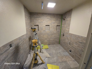 Bathroom tiling project in progress, showing a laser level and ladder, handled by Torres Services in Anchorage, AK.