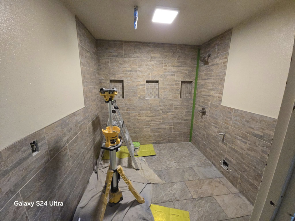 Bathroom tiling project in progress, showing a laser level and ladder, handled by Torres Services in Anchorage, AK.