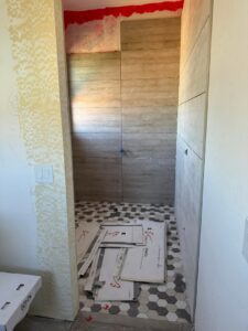 A bathroom renovation in progress, showing newly tiled walls and a hexagonal floor by Kelso Custom Builders, Inc. in Phoenix, AZ.