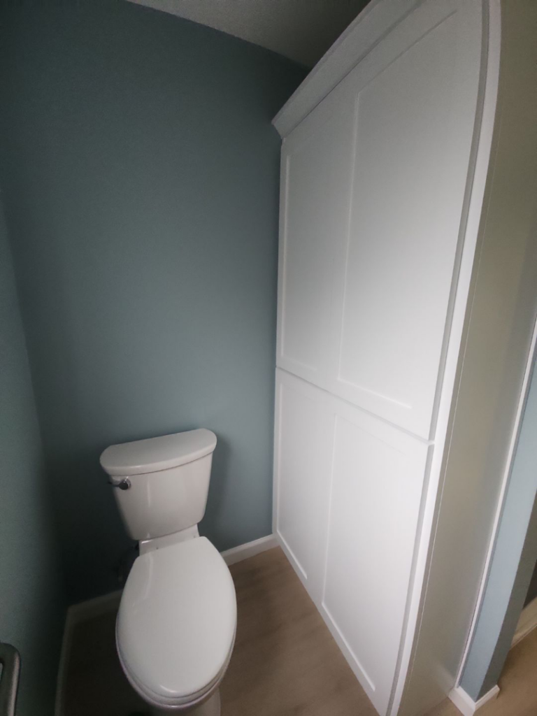 A newly installed toilet and tall storage cabinet in a renovated bathroom by Leupitz Contractors Inc in Salem, OR.