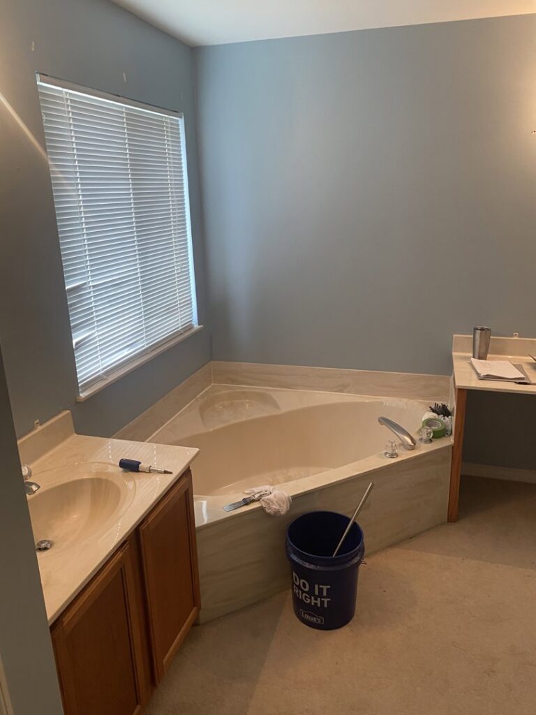 A bathroom with a corner tub and vanity, showing tools indicating work in progress by Newhouse Construction St Louis in St. Louis, MO.