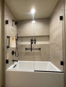 A bathroom tub and shower remodel with a sleek glass enclosure and modern black fixtures by Boisen Remodeling LLC in Appleton, WI.