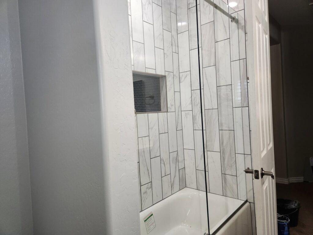 A bathroom remodel featuring a white subway tile tub and shower combination by LJ Builders in Chandler, AZ