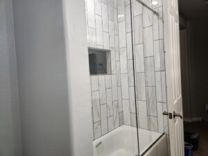 A bathroom remodel featuring a white subway tile tub and shower combination by LJ Builders in Chandler, AZ