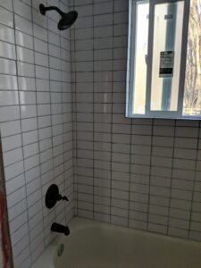 Newly tiled bathroom tub and shower with black fixtures by J & D Home Innovations in West Jordan, UT