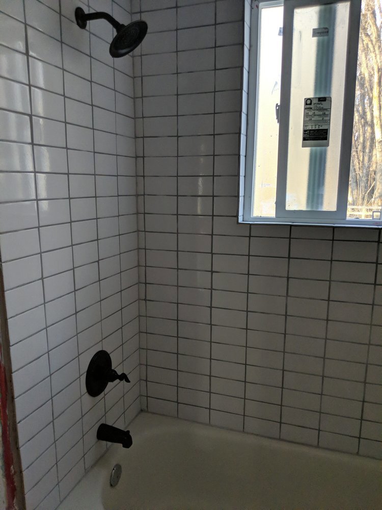 Newly tiled bathroom tub and shower with black fixtures by J & D Home Innovations in West Jordan, UT