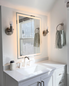 A newly installed bathroom vanity with a modern sink, lighted mirror, and wall sconces by Home Style Improvement in Frederick, MD.