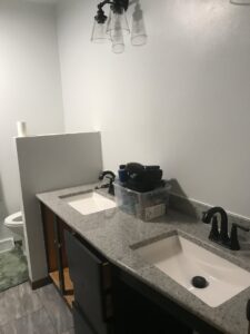 A bathroom with a new vanity, sinks, and light fixture installed by Ace Handyman Services in North Kingstown, RI