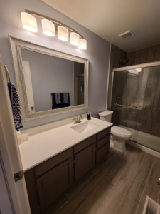 A renovated bathroom featuring a new vanity, mirror, and tiled shower by QCON LLC in Aurora, CO.