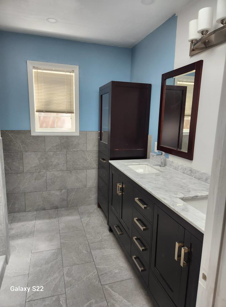 A renovated bathroom featuring a new vanity, mirror, and tiled floor by Ryan Moon Construction and Custom Tile LLC in Eugene, OR.