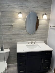Renovated bathroom with new vanity, mirror, lighting, and shiplap wall by Top Notch Contracting in Racine, WI.
