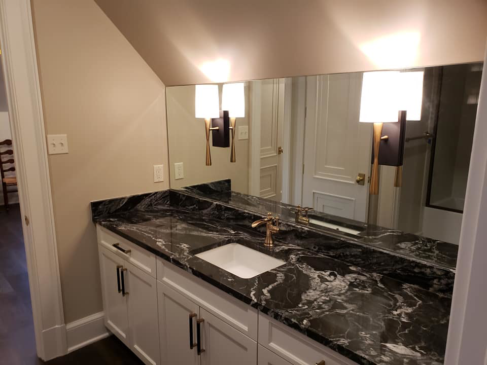 A newly installed bathroom vanity with a black marble countertop, sink, and modern fixtures by Kenneth C. Bergeron, Architect in Pollock, LA.
