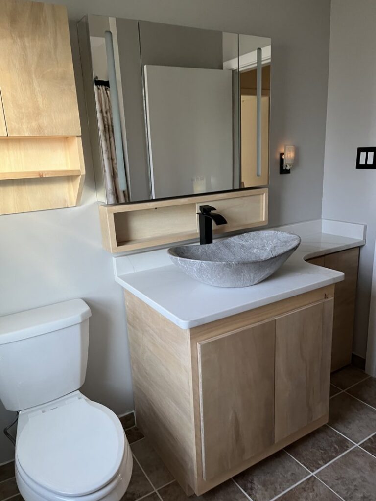A modern bathroom vanity with a unique bowl sink and mirror, installed by Modern Remodel Build & Design in Worcester, MA.