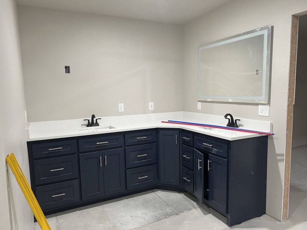 A newly installed bathroom vanity with dark blue cabinets and white quartz countertops by Javier's Countertops in Springdale, AR