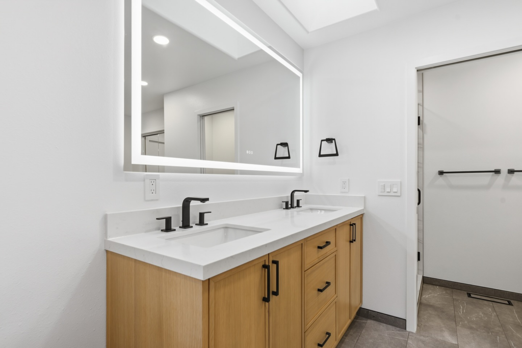 New bathroom vanity with double sinks and an illuminated mirror installed by BelRed Construction in Bellevue, WA.