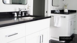 A modern bathroom vanity with a white cabinet, black countertop, and chrome faucet, installed by Thimijan Custom Homes LLC in Rochester, MN