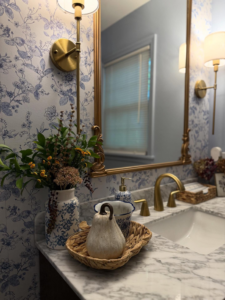 A beautifully updated bathroom vanity with a new faucet, mirror, and wall sconces, showcasing handyman services by Husband for Hire in Suffolk, VA.