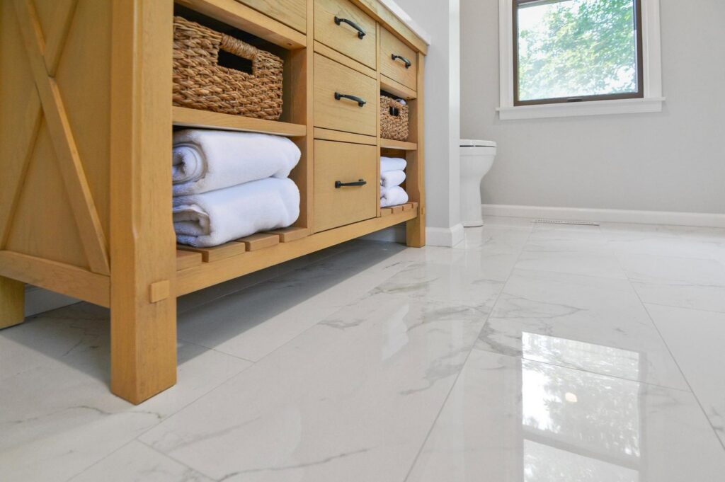 A newly installed wooden bathroom vanity and white marble floor tiles by Total Craftsmen in Towson, MD