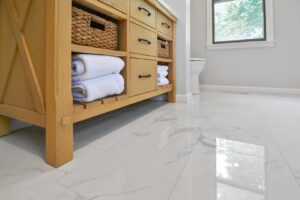 A newly installed wooden bathroom vanity and white marble floor tiles by Total Craftsmen in Towson, MD