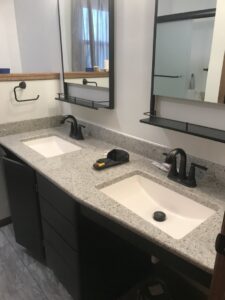 A newly installed bathroom vanity with dual sinks and black fixtures by Ace Handyman Services in North Kingstown, RI