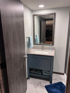 A newly installed bathroom vanity with a blue cabinet, white countertop, and mirror by M.R. Renovations, LLC in Maple Grove, MN.
