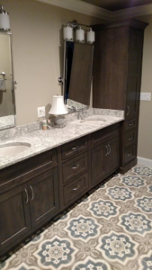 Bathroom vanity with double sinks, dark cabinets, and patterned floor tiles by Coastal Contracting Services Inc., Virginia Beach, VA.