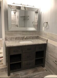 A newly installed bathroom vanity with granite countertop and large mirror by Grizzly Renovations in Naperville, IL