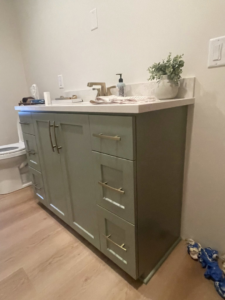 A newly installed green bathroom vanity with a white countertop and gold faucet, a handyman service from K&T PRO Painting in St. Cloud, MN.