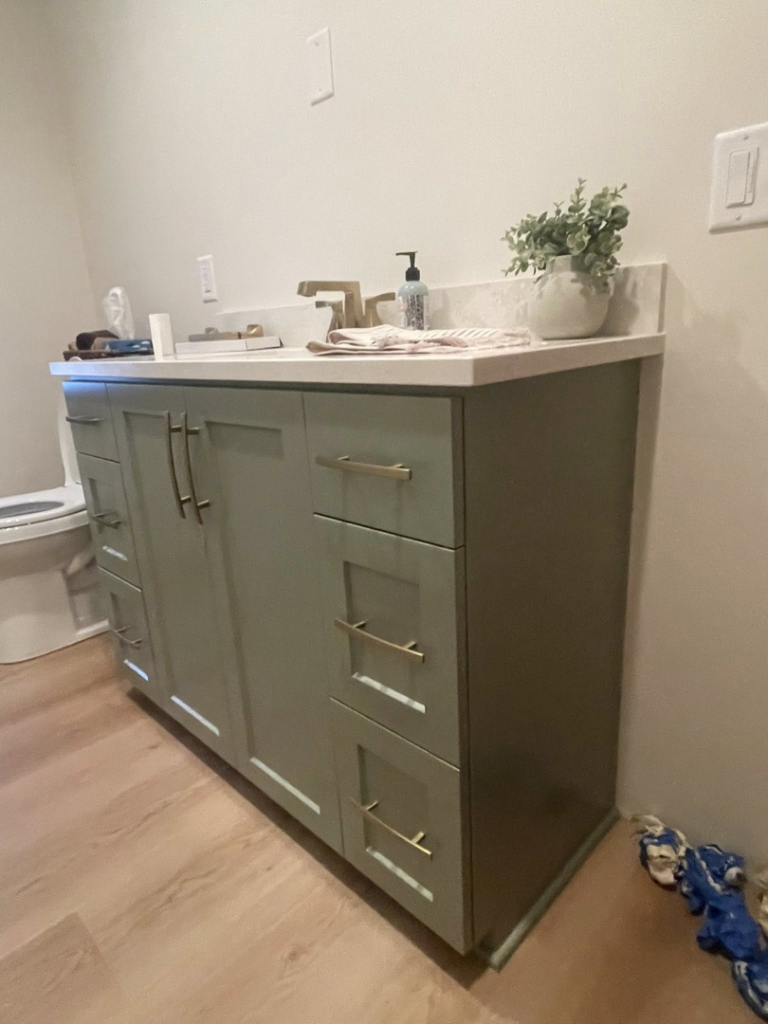 A newly installed green bathroom vanity with a white countertop and gold faucet, a handyman service from K&T PRO Painting in St. Cloud, MN.