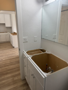 A new bathroom vanity cabinet being installed during a home renovation by Bradford Brothers Builders Inc. in Cape Coral, FL