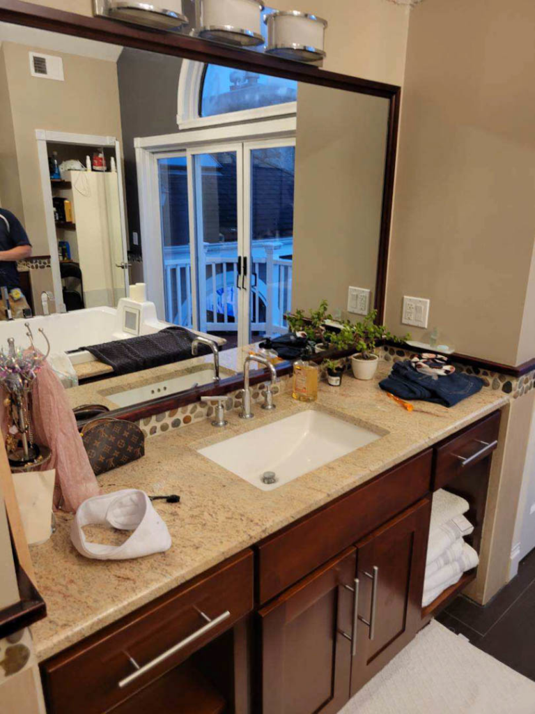 A newly installed bathroom vanity with a sink and large mirror by Infinite Construction LLC in Bristol, CT.